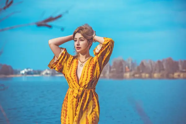 Woman in yellow cotton dress and golden accessorize like a sun. Natural women\'s beauty without retouch, nature background