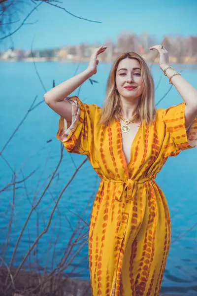 Woman in yellow cotton dress and golden accessorize like a sun. Natural women\'s beauty without retouch, nature background