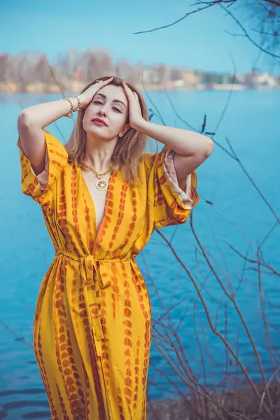 Woman in yellow cotton dress and golden accessorize like a sun. Natural women's beauty without retouch, nature background