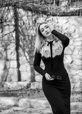 Klasik siyah uzun elbiseli, boynunda beyaz dantelli orta yaşlı bir bayan. Şık kıyafet.