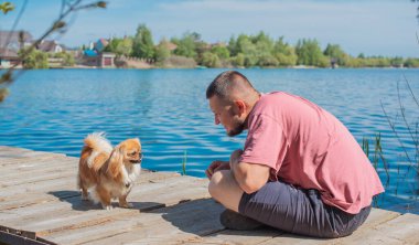 Küçük altın bir Asyalı köpeği olan genç bir adam, evcil hayvan davranış konsepti. İnsan en iyi arkadaşı