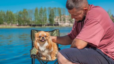 Küçük altın bir Asyalı köpeği olan genç bir adam, evcil hayvan davranış konsepti. İnsan en iyi arkadaşı