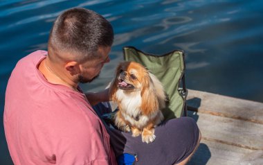 Küçük altın bir Asyalı köpeği olan genç bir adam, evcil hayvan davranış konsepti. İnsan en iyi arkadaşı