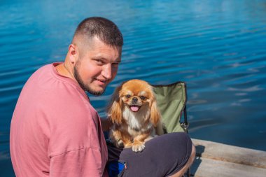 Küçük altın bir Asyalı köpeği olan genç bir adam, evcil hayvan davranış konsepti. İnsan en iyi arkadaşı