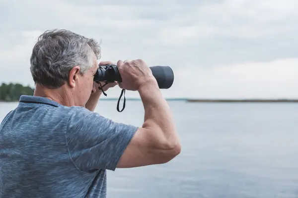 stock image  European Mature man looking in a binoculars . Hobby and recreation concept