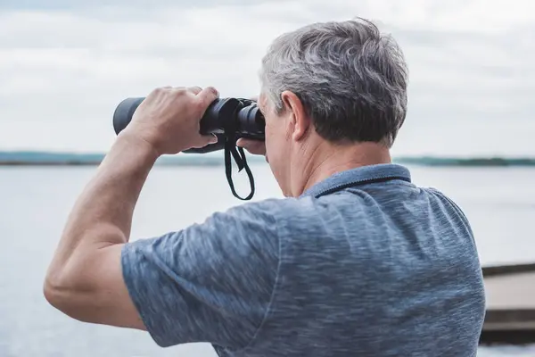 stock image  European Mature man looking in a binoculars . Hobby and recreation concept