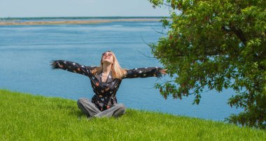 Enerji iyileştirme ve meditasyon konsepti, çimenlerin üzerinde dinlenen ve dinlenen bir kadın.