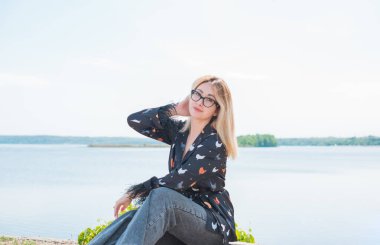 Sıradan kıyafetli pijama stili. Kadın ipek bluz ve kot pantolon giyer ve dışarıda dinlenir.