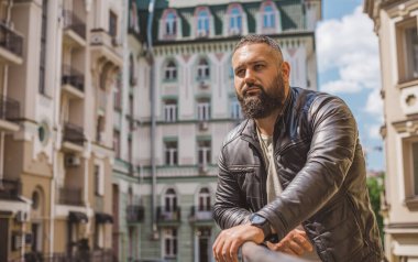 Büyük Avrupalı yarı Arap bir adam, deri ceket giyiyor, yakışıklı bir adamın portresini çiziyor.