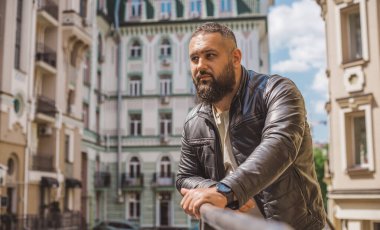 Büyük Avrupalı yarı Arap bir adam, deri ceket giyiyor, yakışıklı bir adamın portresini çiziyor.