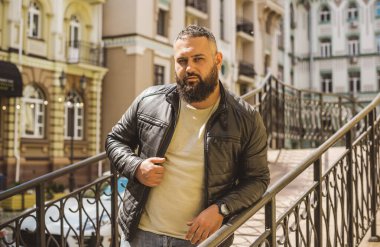 Büyük Avrupalı yarı Arap bir adam, deri ceket giyiyor, yakışıklı bir adamın portresini çiziyor.