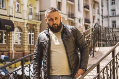 Büyük Avrupalı yarı Arap bir adam, deri ceket giyiyor, yakışıklı bir adamın portresini çiziyor.