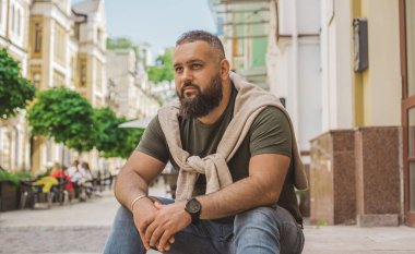 Kıyafet modası, yakışıklı bir adamın portresi. Şık tişörtlü, kot pantolonlu Avrupalı yarı Arap erkekler.