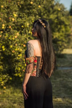 Siyah saçlı kadın, siyah elbiseli, arka planda, korse etnik baskılar, Slav tarzı. 