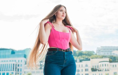 Gençlik konsepti. Güzel, güzel Slav güzeli, uzun sarı saçlı, pembe bluzlu ve açık havada kotlu bir kız.