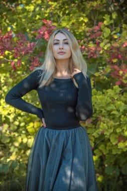 Bahçede duran siyah tonları olan zarif bir kadın. Güzel kadınsı görünüş