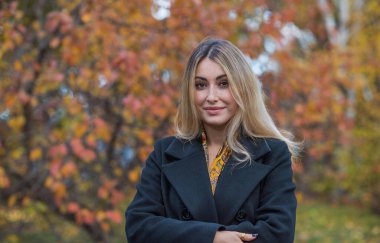 Siyah yün ceketli sarı saçlı kadın ve altın atkı, kadınlar için moda, gerçek açık hava fotoğrafı.