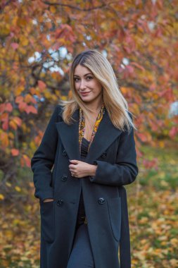 Siyah yün ceketli sarı saçlı kadın ve altın atkı, kadınlar için moda, gerçek açık hava fotoğrafı.