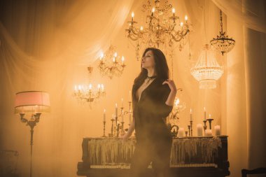 Efsanevi akşam atmosferinde siyah uzun saçlı, siyah elbiseli zarif bir kadın.