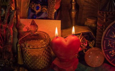 Aşk büyüsü, büyüler ve hayatta çekici bir ilişki. Masada yanan kırmızı kalp mumu.