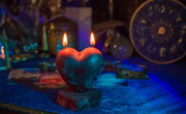 Aşk büyüsü, büyüler ve hayatta çekici bir ilişki. Masada yanan kırmızı kalp mumu.