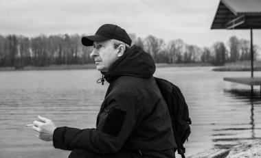 Büyük bir metropolün sakini olan yaşlı bir adam sağlıksız bir hayat sürüyor, parkta oturuyor ve sigara içiyor.