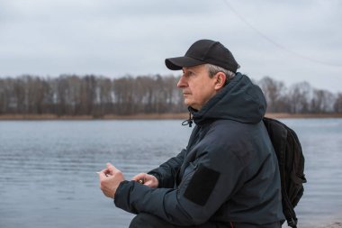 Büyük bir metropolün sakini olan yaşlı bir adam sağlıksız bir hayat sürüyor, parkta oturuyor ve sigara içiyor.