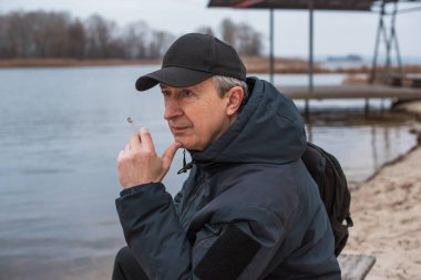 Büyük bir metropolün sakini olan yaşlı bir adam sağlıksız bir hayat sürüyor, parkta oturuyor ve sigara içiyor.