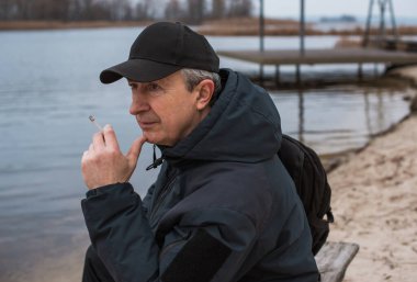 Büyük bir metropolün sakini olan yaşlı bir adam sağlıksız bir hayat sürüyor, parkta oturuyor ve sigara içiyor.