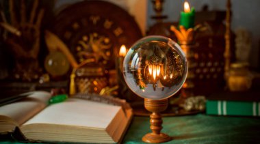 Parlayan mumların, antik tarot kartlarının, kristal kürenin ve sihirli ayin aletlerinin yer aldığı güzel düzenlenmiş bir cadı sunağı sahnesi. Bu atmosferik bileşim mistik enerjinin, ruhani uygulamanın ve esrarengiz zarafetin özünü çağrıştırıyor.