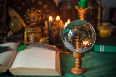 Parlayan mumların, antik tarot kartlarının, kristal kürenin ve sihirli ayin aletlerinin yer aldığı güzel düzenlenmiş bir cadı sunağı sahnesi. Bu atmosferik bileşim mistik enerjinin, ruhani uygulamanın ve esrarengiz zarafetin özünü çağrıştırıyor.