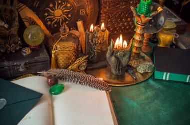 Parlayan mumların, antik tarot kartlarının, kristal kürenin ve sihirli ayin aletlerinin yer aldığı güzel düzenlenmiş bir cadı sunağı sahnesi. Bu atmosferik bileşim mistik enerjinin, ruhani uygulamanın ve esrarengiz zarafetin özünü çağrıştırıyor.