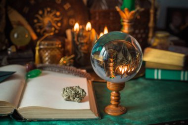Parlayan mumların, antik tarot kartlarının, kristal kürenin ve sihirli ayin aletlerinin yer aldığı güzel düzenlenmiş bir cadı sunağı sahnesi. Bu atmosferik bileşim mistik enerjinin, ruhani uygulamanın ve esrarengiz zarafetin özünü çağrıştırıyor.