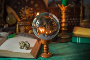 Parlayan mumların, antik tarot kartlarının, kristal kürenin ve sihirli ayin aletlerinin yer aldığı güzel düzenlenmiş bir cadı sunağı sahnesi. Bu atmosferik bileşim mistik enerjinin, ruhani uygulamanın ve esrarengiz zarafetin özünü çağrıştırıyor.