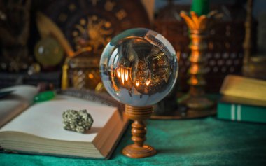 Parlayan mumların, antik tarot kartlarının, kristal kürenin ve sihirli ayin aletlerinin yer aldığı güzel düzenlenmiş bir cadı sunağı sahnesi. Bu atmosferik bileşim mistik enerjinin, ruhani uygulamanın ve esrarengiz zarafetin özünü çağrıştırıyor.