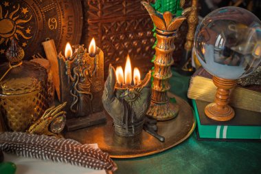 Parlayan mumların, antik tarot kartlarının, kristal kürenin ve sihirli ayin aletlerinin yer aldığı güzel düzenlenmiş bir cadı sunağı sahnesi. Bu atmosferik bileşim mistik enerjinin, ruhani uygulamanın ve esrarengiz zarafetin özünü çağrıştırıyor.