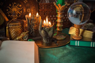 Parlayan mumların, antik tarot kartlarının, kristal kürenin ve sihirli ayin aletlerinin yer aldığı güzel düzenlenmiş bir cadı sunağı sahnesi. Bu atmosferik bileşim mistik enerjinin, ruhani uygulamanın ve esrarengiz zarafetin özünü çağrıştırıyor.