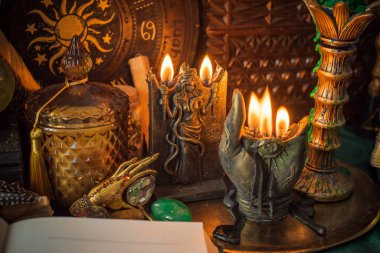 Parlayan mumların, antik tarot kartlarının, kristal kürenin ve sihirli ayin aletlerinin yer aldığı güzel düzenlenmiş bir cadı sunağı sahnesi. Bu atmosferik bileşim mistik enerjinin, ruhani uygulamanın ve esrarengiz zarafetin özünü çağrıştırıyor.