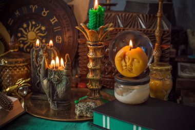 Parlayan mumların, antik tarot kartlarının, kristal kürenin ve sihirli ayin aletlerinin yer aldığı güzel düzenlenmiş bir cadı sunağı sahnesi. Bu atmosferik bileşim mistik enerjinin, ruhani uygulamanın ve esrarengiz zarafetin özünü çağrıştırıyor.