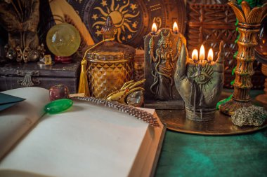 Parlayan mumların, antik tarot kartlarının, kristal kürenin ve sihirli ayin aletlerinin yer aldığı güzel düzenlenmiş bir cadı sunağı sahnesi. Bu atmosferik bileşim mistik enerjinin, ruhani uygulamanın ve esrarengiz zarafetin özünü çağrıştırıyor.