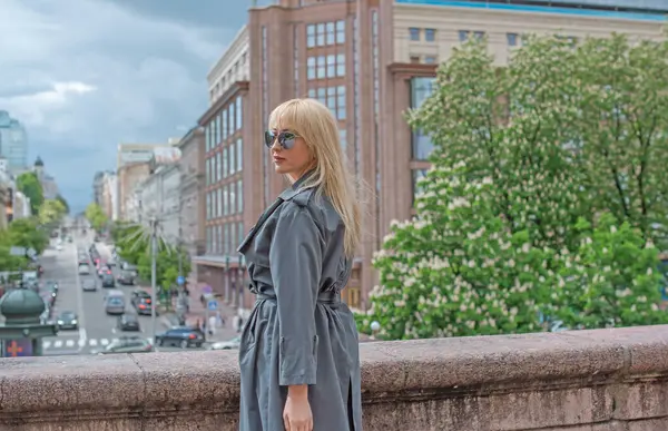 Kendine güveni tam Avrupalı bir kadın Gri montlu, Kentsel Yürüyüşün tadını çıkarıyor