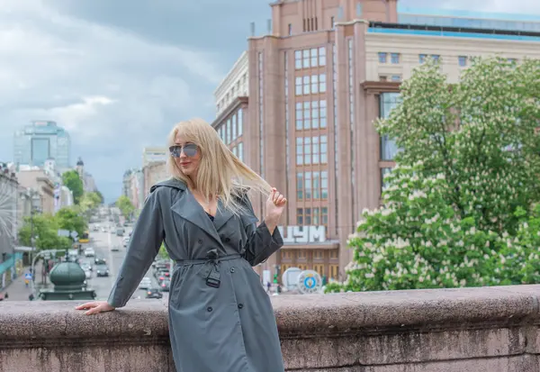 Kendine güveni tam Avrupalı bir kadın Gri montlu, Kentsel Yürüyüşün tadını çıkarıyor