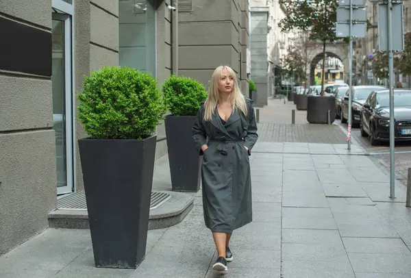 Kendine güveni tam Avrupalı bir kadın Gri montlu, Kentsel Yürüyüşün tadını çıkarıyor