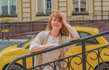 Zarif, olgun, kızıl saçlı, beyaz elbiseli, güzel Avrupalı bir kadın. Şehir Caddesinde Şehir Yürüyüşü 'nün tadını çıkarıyor.