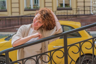 Zarif, olgun, kızıl saçlı, beyaz elbiseli, güzel Avrupalı bir kadın. Şehir Caddesinde Şehir Yürüyüşü 'nün tadını çıkarıyor.