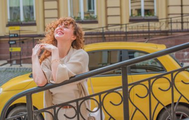 Zarif, olgun, kızıl saçlı, beyaz elbiseli, güzel Avrupalı bir kadın. Şehir Caddesinde Şehir Yürüyüşü 'nün tadını çıkarıyor.