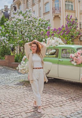 Zarif, olgun, kızıl saçlı, beyaz elbiseli, güzel Avrupalı bir kadın. Şehir Caddesinde Şehir Yürüyüşü 'nün tadını çıkarıyor.