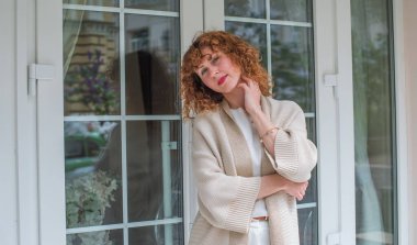 Zarif, olgun, kızıl saçlı, beyaz elbiseli, güzel Avrupalı bir kadın. Şehir Caddesinde Şehir Yürüyüşü 'nün tadını çıkarıyor.