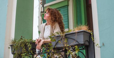 Zarif, olgun, kızıl saçlı, beyaz elbiseli, güzel Avrupalı bir kadın. Şehir Caddesinde Şehir Yürüyüşü 'nün tadını çıkarıyor.