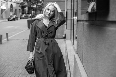 Gri ceketli olgun Avrupalı sarışın kadın şehir merkezinde yürüyor, modaya uygun trendler.